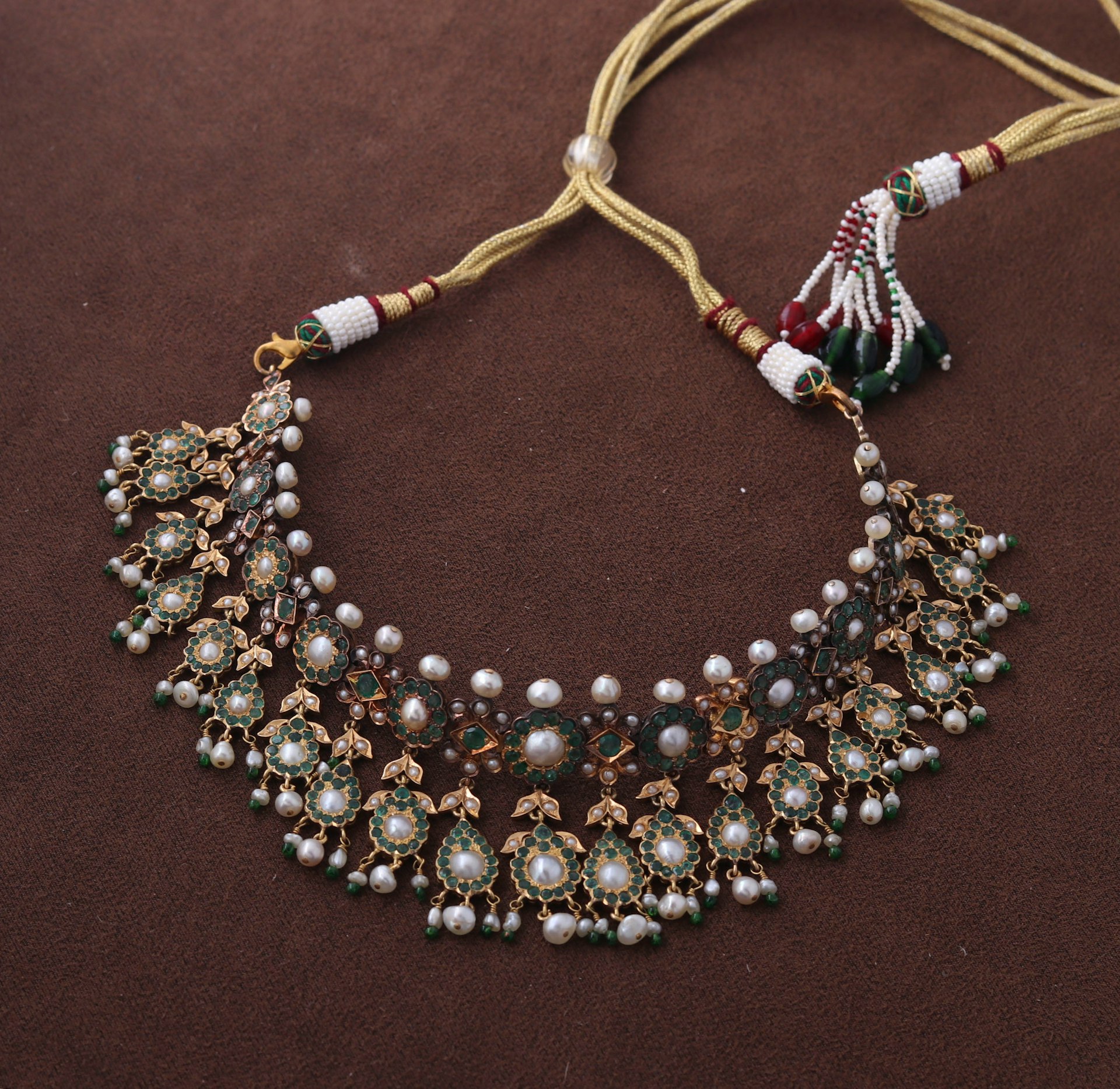 A necklace with pearls and beads on a brown surface